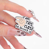 This Close To Losing It Brooch Enamel Pin holding in a hand